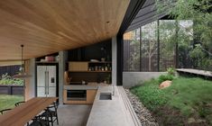 an outdoor kitchen and dining area in a modern home with wood paneling on the walls