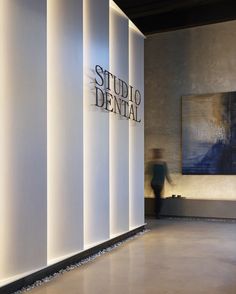 a man is walking past the studio dental sign in front of a wall that reads studio dental