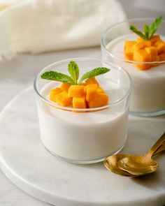 two small glasses filled with yogurt and fruit