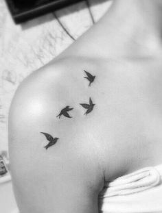 a woman's shoulder with three birds flying in the sky on her left arm