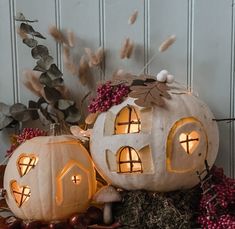 two lighted pumpkins sitting next to each other on top of a pile of leaves