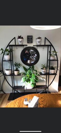 a clock mounted to the side of a wall next to a table with potted plants on it