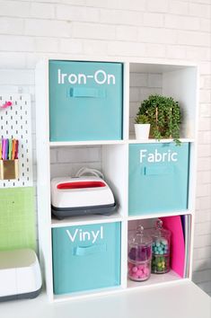 a white desk topped with lots of boxes filled with crafting supplies next to a brick wall