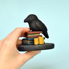 a black bird sitting on top of a stack of books