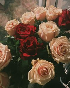 a vase filled with lots of red and white roses