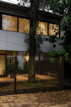 an apartment building with large windows and iron fenced in area next to trees at night