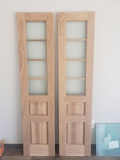 two wooden doors sitting next to each other on top of a hard wood floor in front of a white wall