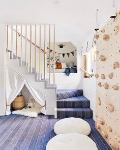 there is a climbing wall in the living room with blue carpet and white rugs