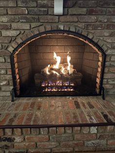 a brick fireplace with fire burning in it