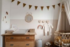 a baby's room with a crib, dresser and hanging clothes on the wall