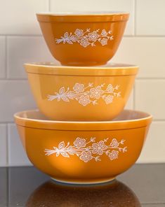 three yellow bowls sitting on top of a counter