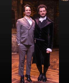 two men standing next to each other on a wooden floor wearing suits and ties with one man in a tuxedo