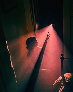 a woman standing in front of a red light with her arm raised up to the ceiling