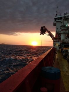 the sun is setting over the ocean as seen from a boat