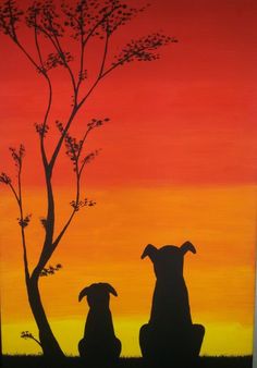 two dogs sitting under a tree in front of a sunset