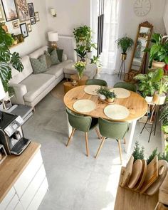 an aerial view of a living room and dining area with couches, coffee table, potted plants and other items