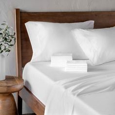 a bed with white sheets and pillows on it