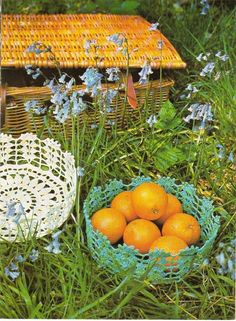 two baskets filled with oranges sitting on top of a grass covered field next to blue flowers