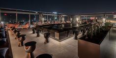 the rooftop bar is lit up at night with lots of chairs and tables on it