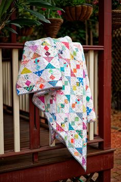 a quilted blanket sitting on top of a wooden bench next to a potted plant