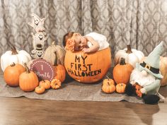 a baby sleeping in a pumpkin surrounded by other halloween decorations