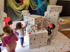 three children playing with cardboard blocks in a room