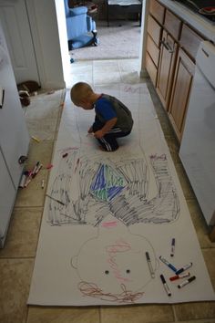 a little boy sitting on the floor drawing with crayons