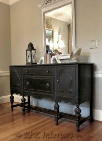 a black dresser with an ornate mirror above it on top of a hard wood floor