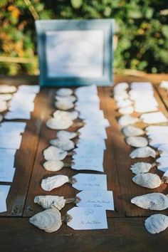 the table is set up with shells and place cards for guests to write their names