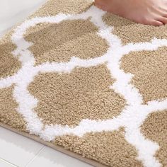 a person standing on top of a brown and white rug next to a bathroom floor