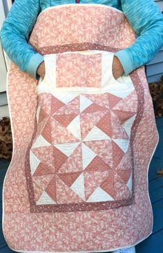 a woman is holding a quilt in her hands