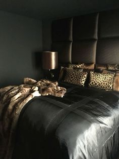 a large bed with leopard print pillows and blankets on it's headboard in a dark room