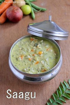 there is a small metal bowl filled with soup on the table next to some vegetables