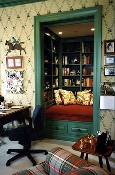 a living room filled with furniture and bookshelves next to a wallpapered wall