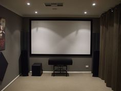 an empty room with a projector screen and speakers