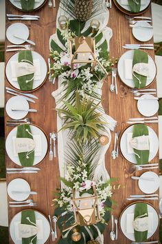 the table is set with white plates, silverware and green napkins on it