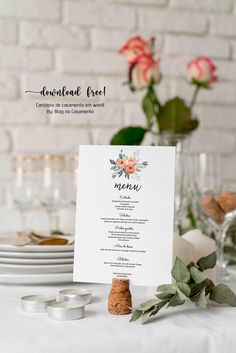 the menu card is placed on top of a white table cloth with flowers and greenery