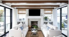 a living room filled with white couches and a flat screen tv mounted above the fireplace