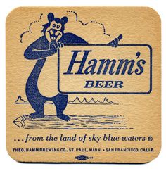 a coaster with a bear holding a sign that says hamm's beer from the land of sky blue waters