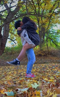 a man and woman are hugging in the leaves