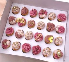 a box filled with lots of cupcakes covered in pink frosting and decorations