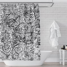 a white bath tub sitting next to a shower curtain covered in lots of grafitti