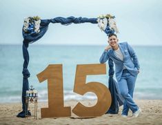 a man in a blue suit standing next to a large number 15 on the beach