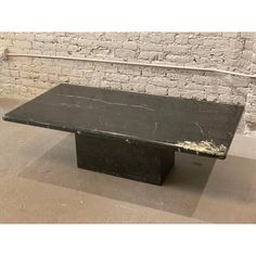 a black marble table sitting in front of a brick wall