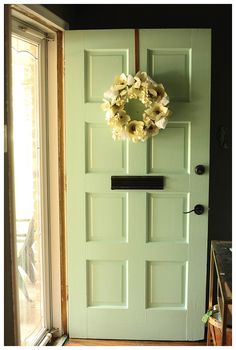 a green door with a wreath hanging on it