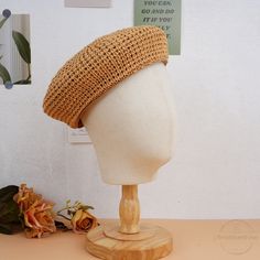 a white mannequin head wearing a straw hat on top of a wooden stand