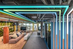 the interior of an office building with colorful lighting and large couches in front of it