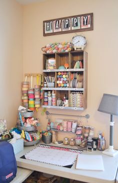 a craft room with lots of crafting supplies on the desk and shelves above it