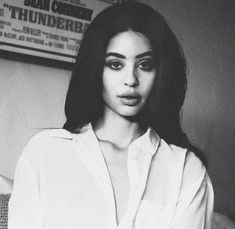 a black and white photo of a woman with long dark hair wearing a white shirt