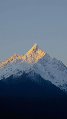 the top of a snow covered mountain at sunset